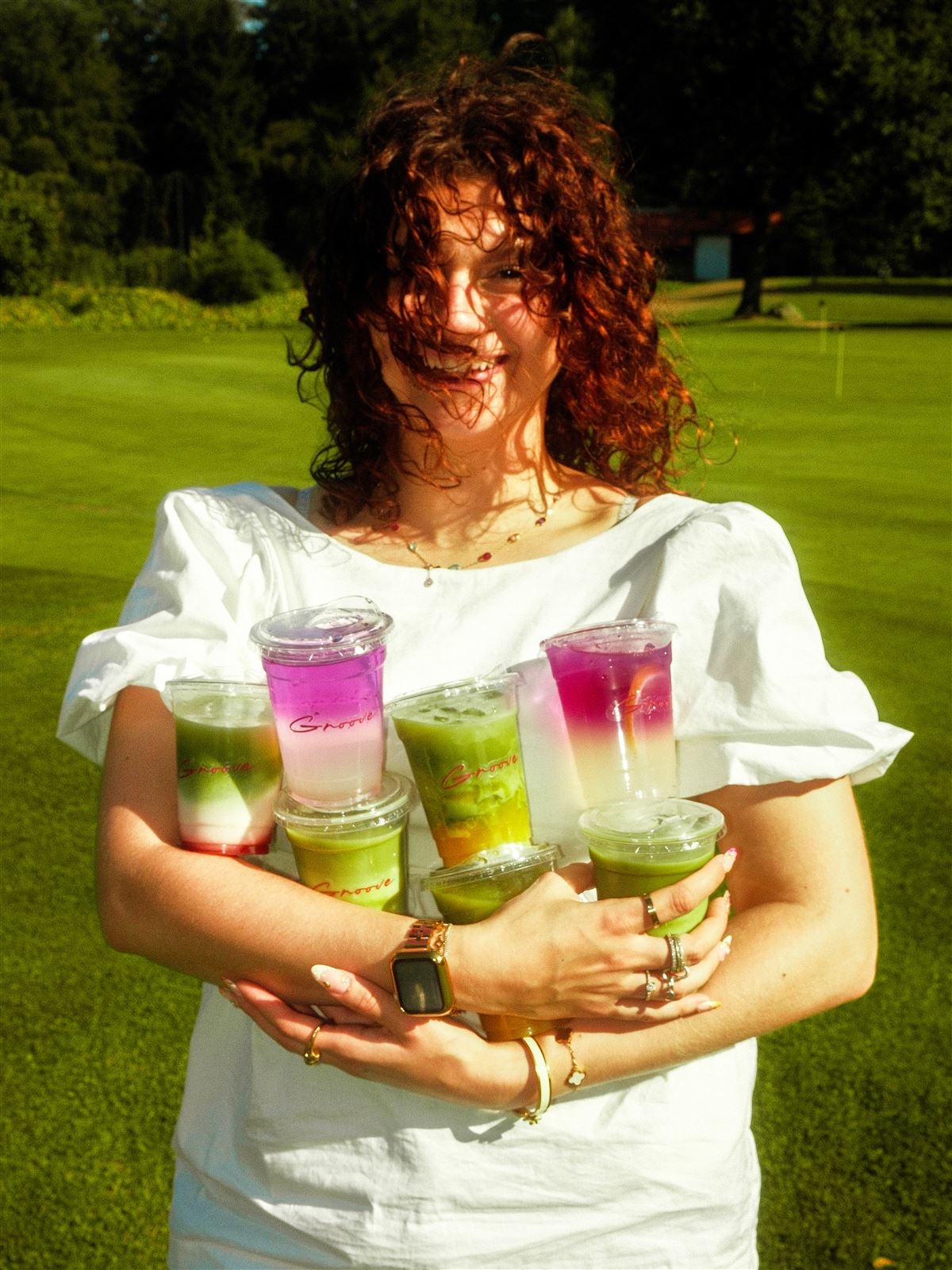 Arme voller bunter Groove-Matcha-Drinks auf einer sonnigen Wiese