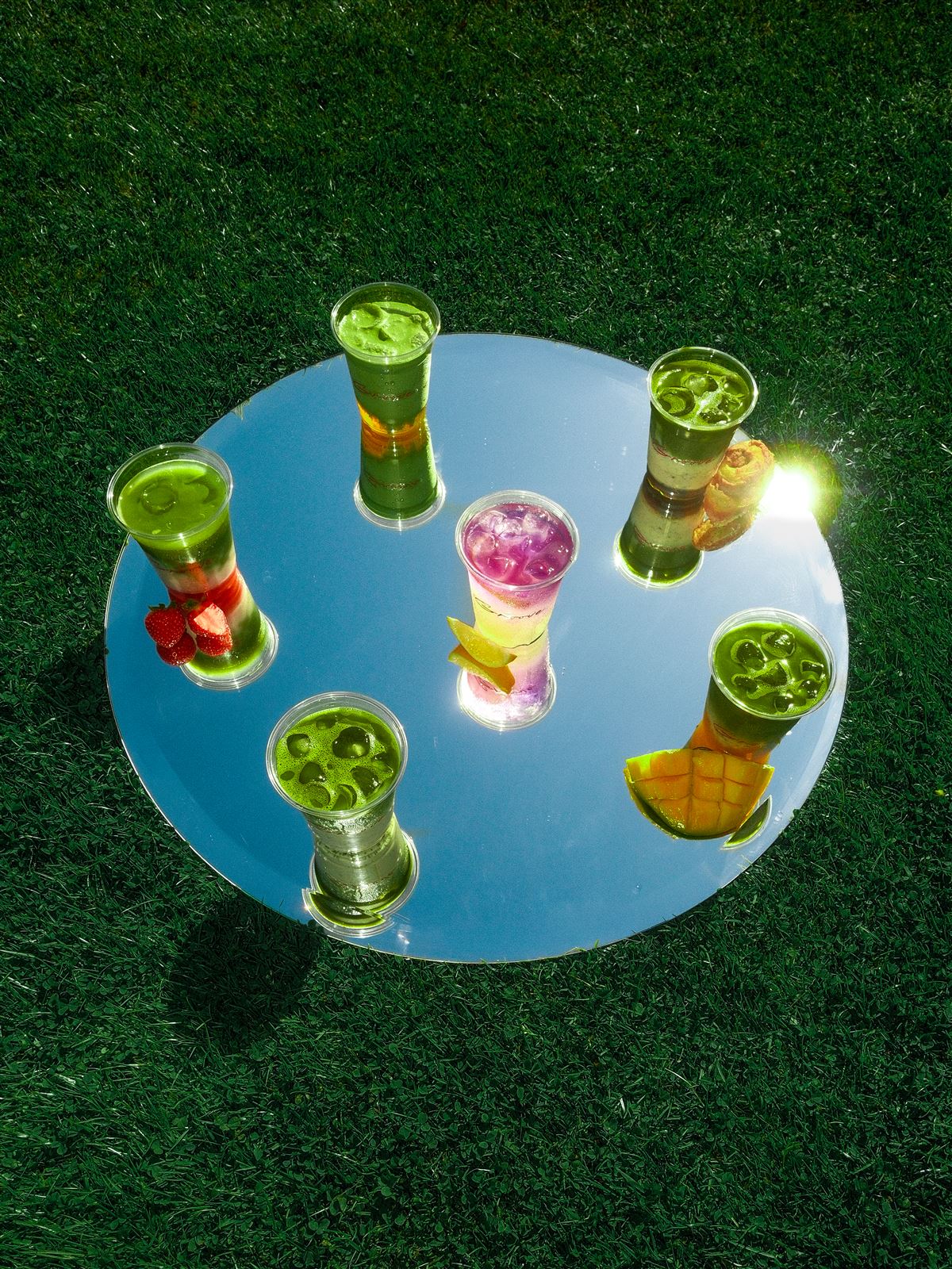 Sechs Groove-Drinks auf einem runden Spiegel im Gras
